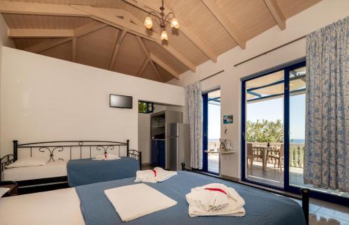 a bedroom with two beds and a large window at Mikro Nisi Studios & Apartments in Agios Nikolaos