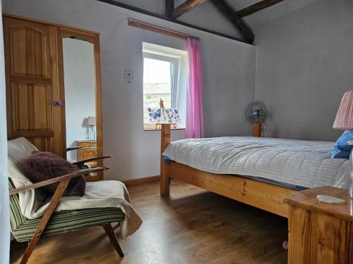 Un dormitorio con una cama y una silla y una ventana. en Balkan Barn, en Tŭzha