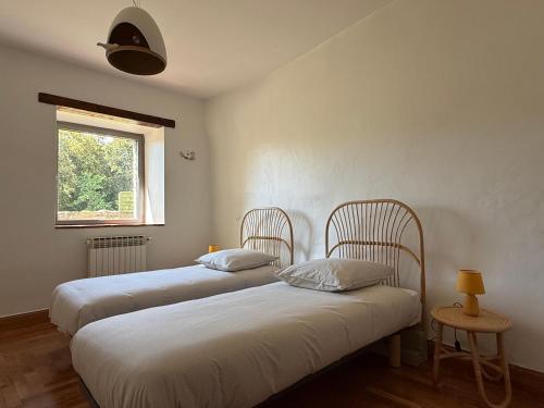 deux lits dans une chambre avec une fenêtre dans l'établissement Valboissière Mas avec piscine, à Brissac