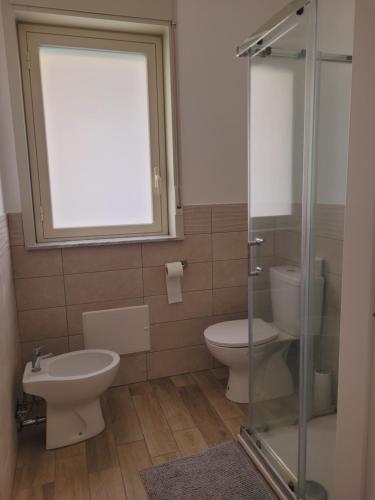 a bathroom with a toilet and a glass shower at HOUSE AIRPORT Catania 4 in CTA