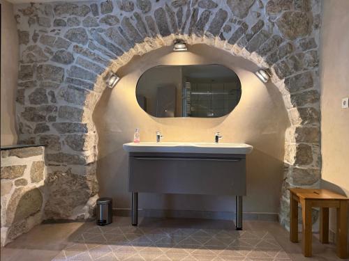 La salle de bains est pourvue d'un lavabo et d'un mur en pierre. dans l'établissement Valboissière Mas avec piscine, à Brissac
