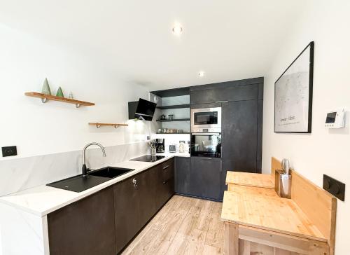 une cuisine avec des armoires noires et blanches et un évier dans l'établissement Le Mimi Shelter - Nouveau à Valloire - APT 6 pers, à Valloire