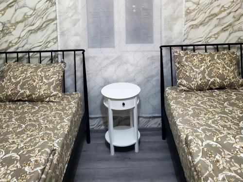 a small white table between two beds in a room at Central House in Kutaisi