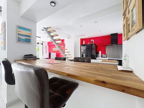 a kitchen with a long wooden counter and chairs at La Villa Palladio, Calme et Détente in Montpellier