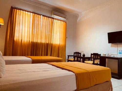 Una habitación de hotel con dos camas, un escritorio y una ventana. en Jati Hotel, en Ternate