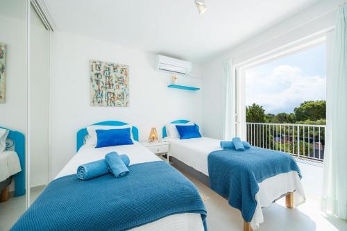 two beds in a room with a window at Des Port - Vistas al mar in Portopetro