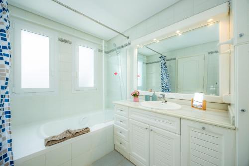 a white bathroom with a sink and a mirror at Des Port - Vistas al mar in Portopetro
