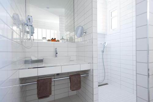 a white bathroom with a sink and a shower at La Frégate in Cap-Ferret