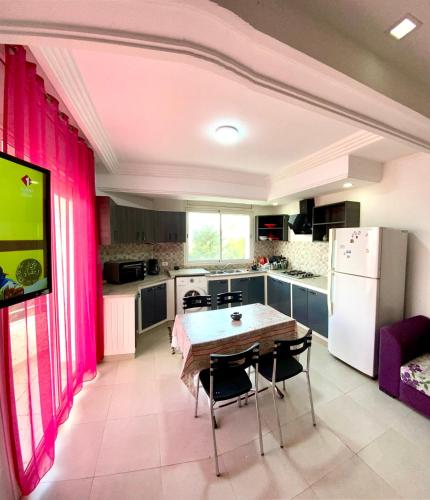 a kitchen with pink curtains and a table with chairs at Duplex El mansoura A3 in Kelibia