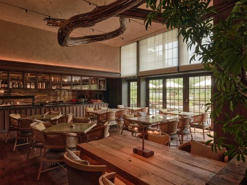 a restaurant with wooden tables and chairs and windows at Patina Osaka in Osaka