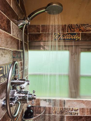 a shower in a bathroom with water coming out of it at American School Bus Glamping with Hot Tub in Woolacombe! in Lee