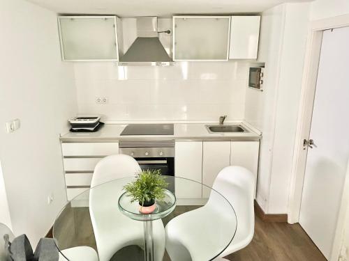 a small kitchen with a glass table and white chairs at La Casina de Cudillero in Cudillero