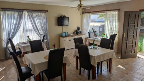 a dining room with tables and chairs and a tv at Amarachi Guesthouse in Swakopmund