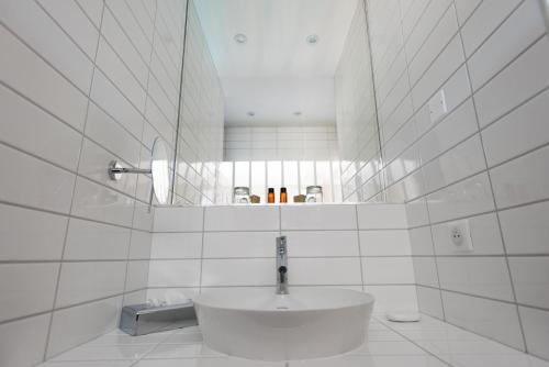 a white bathroom with a sink and a mirror at La Frégate in Cap-Ferret