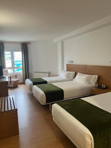 a hotel room with two beds and a couch at Hotel Crisol de las Rías in Miño
