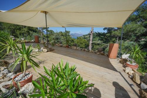 a wooden deck with a large tan umbrella at Ramitos Hotel in Turunc
