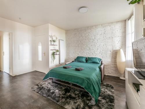 Un dormitorio con una cama verde y una pared de ladrillo blanco. en Appartement Le Petit Monde Magique, en Bailly-Romainvilliers