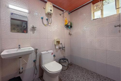 a bathroom with a toilet and a sink at Mayflower Family Lounge -Cochin Airport in Nedumbassery