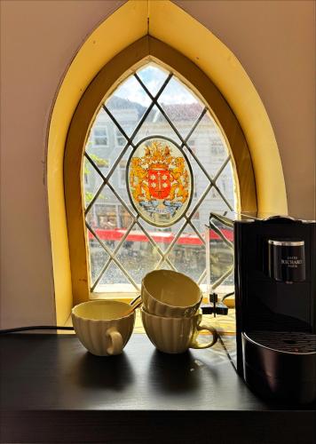 Dos tazas colocadas sobre una mesa frente a una ventana. en The Hazel House, en Haarlem