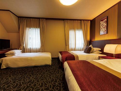 a hotel room with three beds and a television at Shibuya Creston Hotel in Tokyo