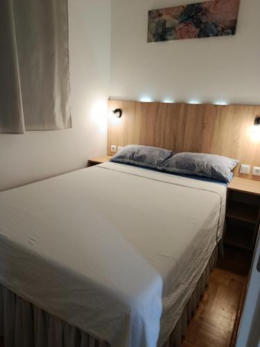 a bedroom with a large white bed with a wooden headboard at Kosmaj in Trebinje