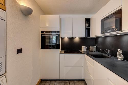 une cuisine avec des armoires blanches et des comptoirs noirs dans l'établissement Apartment Winn, Alpes Travel, Central Chamonix, Sleeps 6, à Chamonix-Mont-Blanc