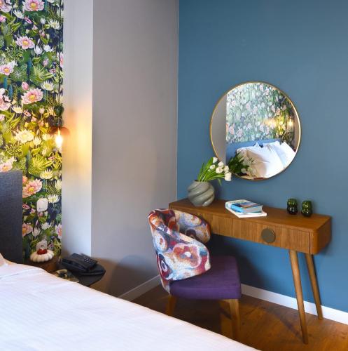 a bedroom with a table with a mirror and a chair at The Oscar Olympic Hotel in Thessaloniki