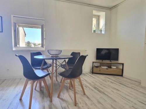 a dining room with a table and chairs and a tv at Le thannaron - Centre ville in Bourg-lès-Valence