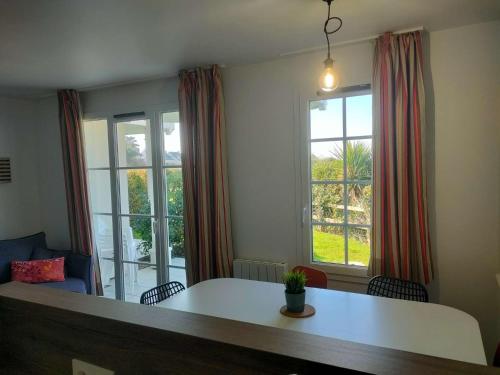 - un salon avec une table et 2 fenêtres dans l'établissement Ref 066 A louer pour les vacances T3 pour 4 personnes avec piscine, à Arzon