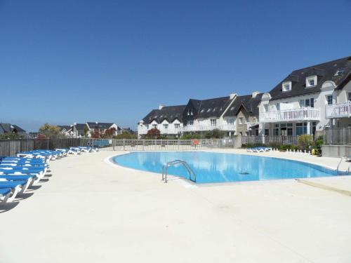 une grande piscine avec des chaises bleues et des maisons dans l'établissement Ref 066 A louer pour les vacances T3 pour 4 personnes avec piscine, à Arzon