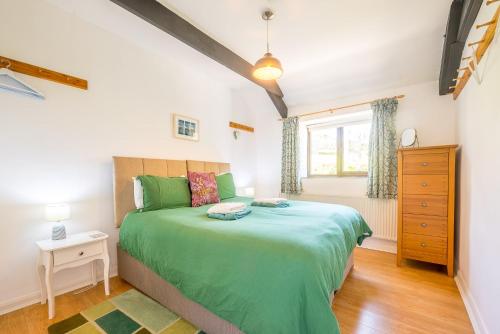 a bedroom with a green bed and a window at Polrunny Farm Elderberry Cottage with sea view in Boscastle