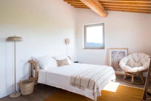 a white bedroom with a bed and a chair at Podere del Bagnolino - Appartamento Belvedere in Santa Luce