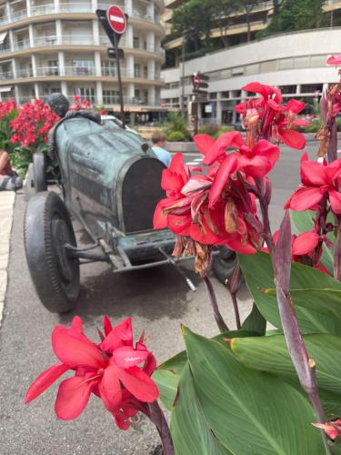 an old car parked on the street with red flowers at Monaco Monte-Carlo door step - Luxury Apartment - 2 Bedrooms 2 Bathrooms - Superb Modern Fully Equipped in Saint-Antoine