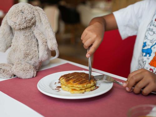 a person eating a plate of pancakes with a fork and knife at Ibis Sfax in Sfax