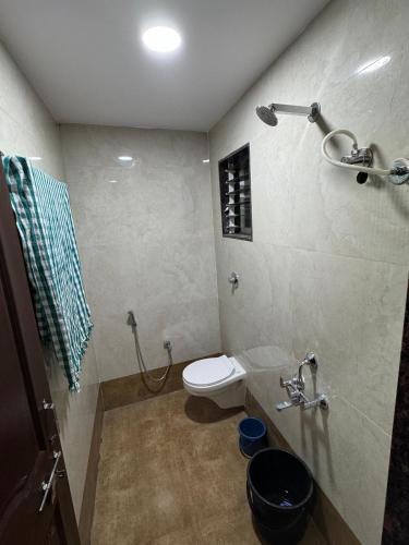 a bathroom with a white toilet and a shower at Gurumauli Guesthouse in Akalkot