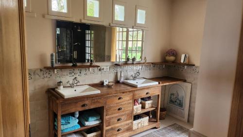 une salle de bain avec deux lavabos et un miroir dans l'établissement Les Vallons, à Gonneville-sur-Mer