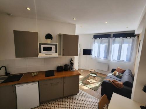 a kitchen and living room with a couch and a microwave at Forest Studio - Ground Floor - City Center - Train station 5 minutes away in Charleville-Mézières