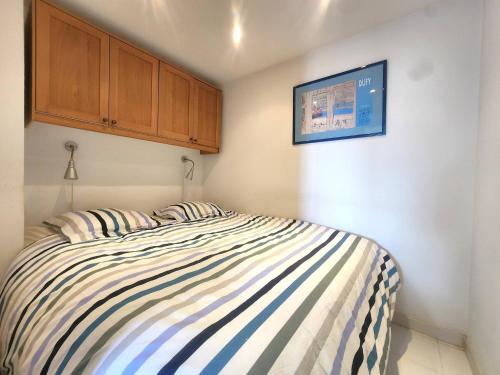 une chambre avec un lit rayé avec une armoire en bois dans l'établissement Magnifique 2p vue mer et piscine, à Théoule-sur-Mer