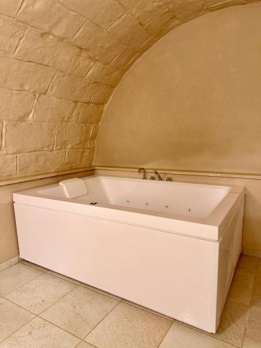 a white bath tub in a room with a brick wall at Dimora Aquae Suites&Spa in Mola di Bari