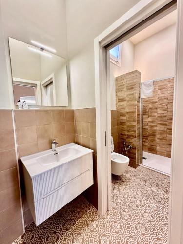 a bathroom with a sink and a toilet and a mirror at Dimora Aquae Suites&Spa in Mola di Bari