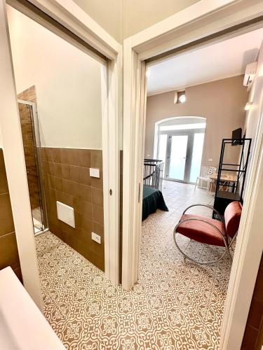 a living room with a red chair and a bathroom at Dimora Aquae Suites&Spa in Mola di Bari