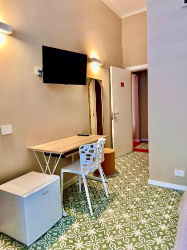 a room with a table and a chair and a flat screen tv at Dimora Aquae Suites&Spa in Mola di Bari