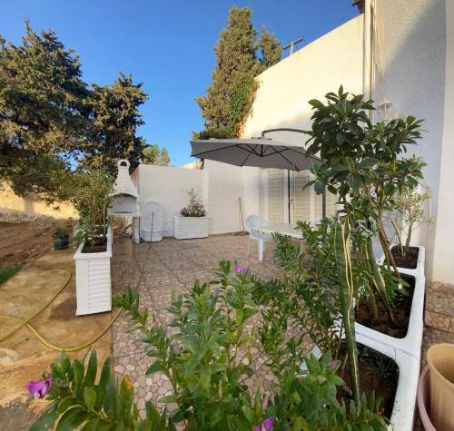 a patio with an umbrella and some plants at Duplex El mansoura A0 in Kelibia