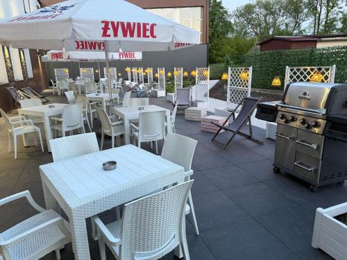 a patio with white tables and chairs and a grill at WRZOS resort & wellness **** DOMKI CAŁOROCZNE in Węgierska Górka