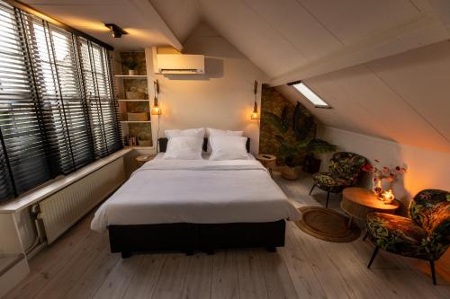 a bedroom with a large bed and two chairs at Huis Delfshaven in Middelburg