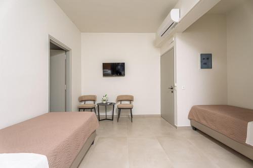a bedroom with two beds and a table and chairs at Emi Seaside in Amoudara Herakliou
