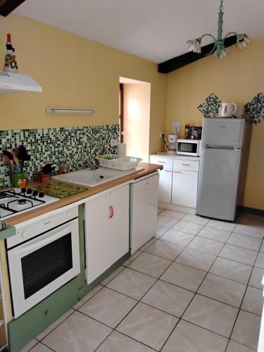 une cuisine avec une cuisinière et un réfrigérateur dans l'établissement Gite du Grand-Pas, à Doulezon