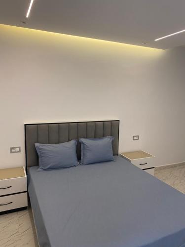 a bedroom with a large bed with blue pillows at Duplex El mansoura A0 in Kelibia