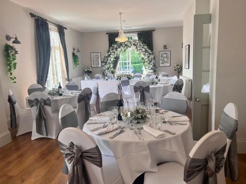 a formal dining room with white tables and chairs at Slepe Hall Hotel in St Ives