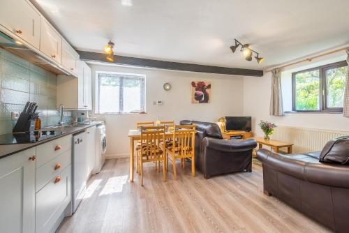 a kitchen and living room with a table and chairs at Polrunny Farm Blackberry Cottage - Cornwall bliss in sight of the sea in Boscastle